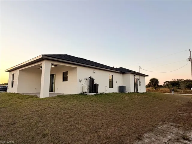 Rear view of property featuring a lawn, stucco siding, a patio area, and ceiling fan