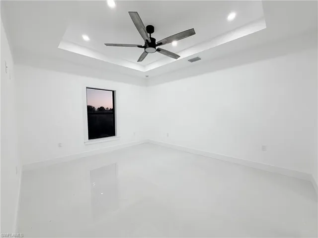 Spare room with a raised ceiling, recessed lighting, ceiling fan, and concrete floors