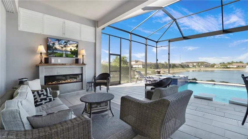 View of patio with a sunroom, a lanai, a pool with connected hot tub, and an outdoor living space with a fireplace