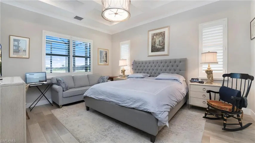 Bedroom featuring coffered ceiling, crown molding, beamed ceiling, and wood finished floors