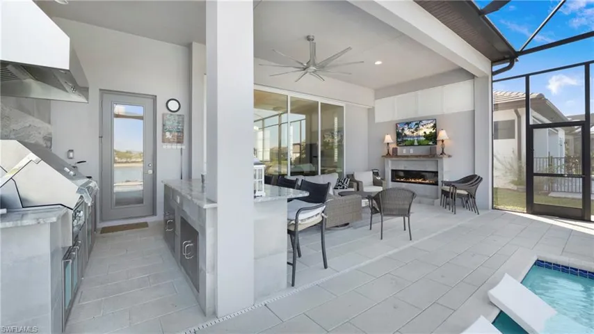 View of patio / terrace featuring ceiling fan, a lanai, a sunroom, a glass covered fireplace, and an outdoor pool