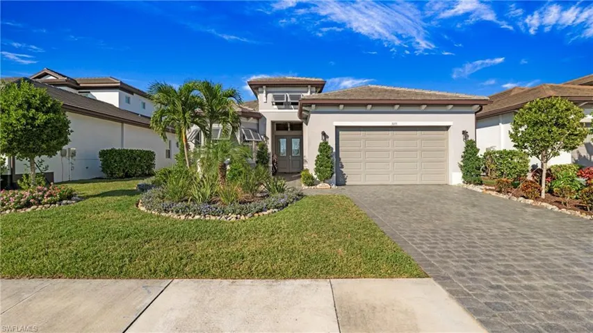 Prairie-style home featuring stucco siding, decorative driveway, a front lawn, and a garage