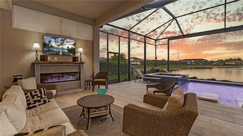 View of pool with glass enclosure, a sunroom, a pool with connected hot tub, a patio area, and an outdoor living space with a fireplace