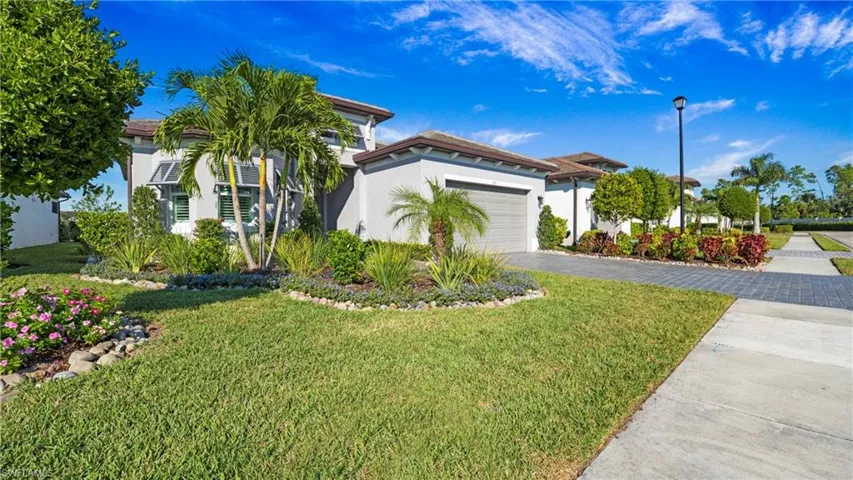 View of front of property with stucco siding, driveway, a front lawn, and an attached garage