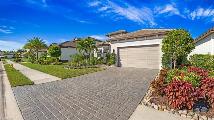View of front facade featuring stucco siding, decorative driveway, a garage, a front yard, and a residential view