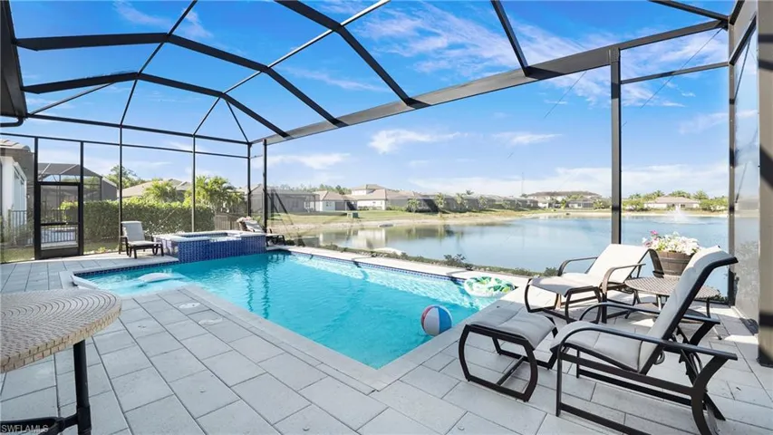 View of pool with a sunroom, a water view, glass enclosure, a pool with connected hot tub, and a patio