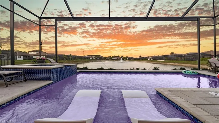 View of SUNSET pool featuring a lanai, a water view, a sunroom, a patio area, and a pool with connected hot tub