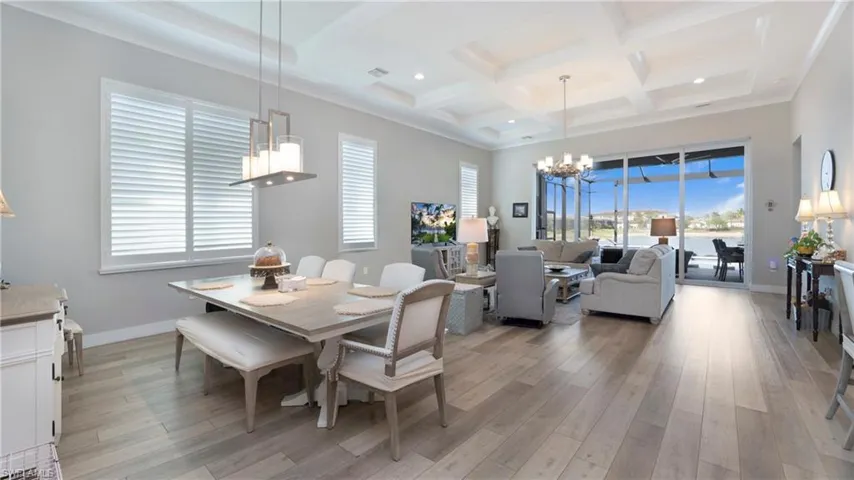 Dining room with a chandelier, light wood-type flooring, coffered ceiling, beamed ceiling, and recessed lighting