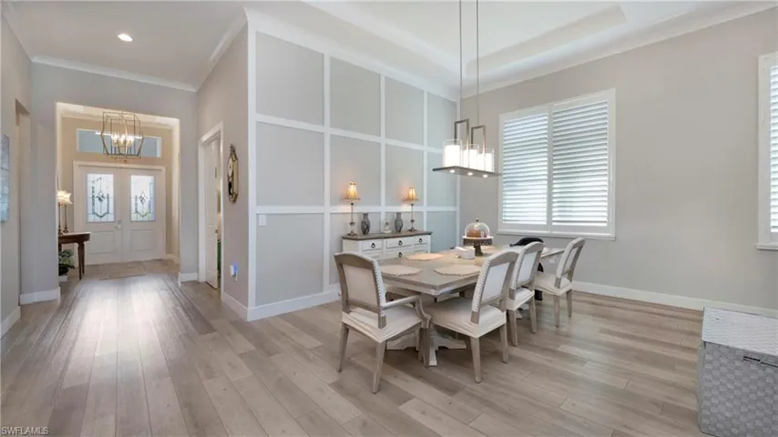 Dining room featuring a chandelier, ornamental molding, healthy amount of natural light, and light wood-type flooring