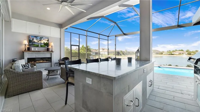 View of patio featuring glass enclosure, a sunroom, a ceiling fan, a glass covered fireplace, and a water view