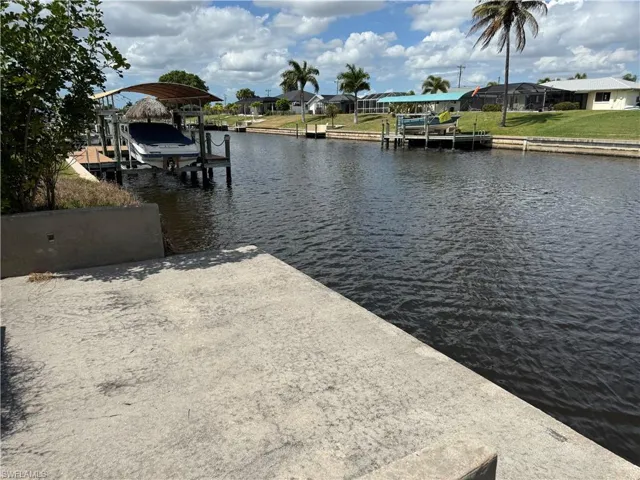 Dock featuring boat lift, a water view, and a residential view
