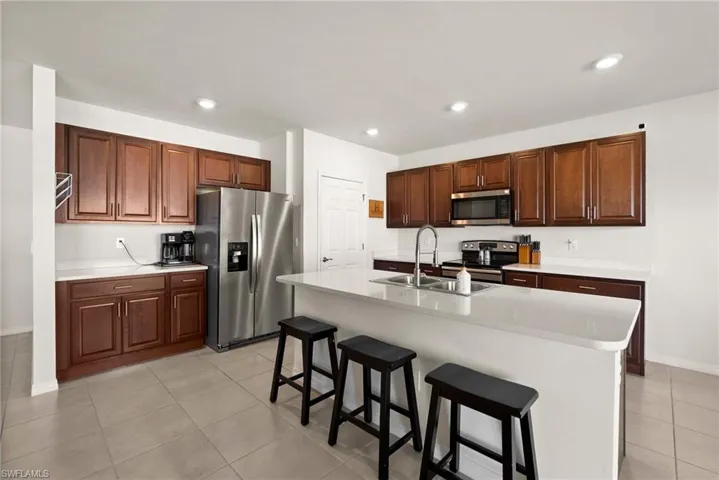 Kitchen with sink, a kitchen breakfast bar, a center island with sink, light tile patterned flooring, and appliances with stainless steel finishes