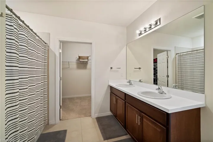 Bathroom with tile patterned flooring, vanity, and curtained shower