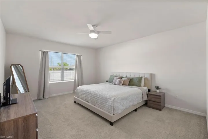 Bedroom with ceiling fan and light colored carpet