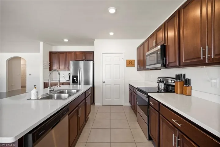 Kitchen featuring light tile patterned floors, sink, and appliances with stainless steel finishes