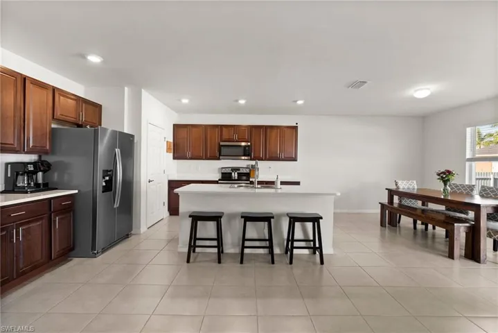 Kitchen featuring a breakfast bar, sink, light tile patterned floors, an island with sink, and appliances with stainless steel finishes