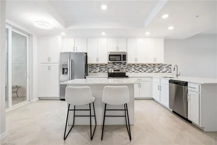 Kitchen featuring white cabinets, stainless steel appliances, a kitchen breakfast bar, a peninsula, and recessed lighting