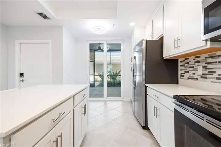Kitchen with white cabinets, tasteful backsplash, range with electric stovetop, and a tray ceiling