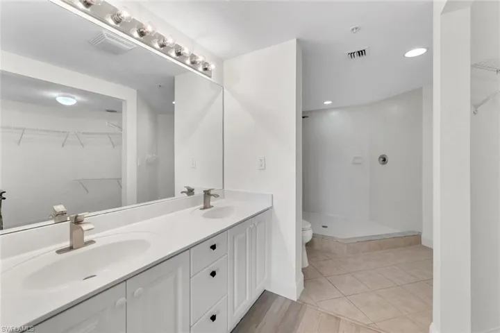 Bathroom featuring tiled shower, tile patterned floors, vanity, and toilet