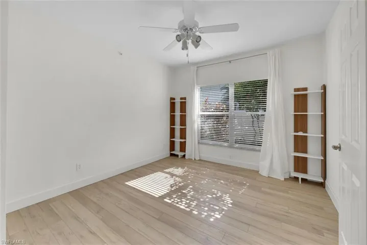 Den with light hardwood / wood-style floors and ceiling fan