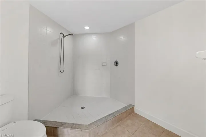 Bathroom with tiled shower, tile patterned floors, and toilet
