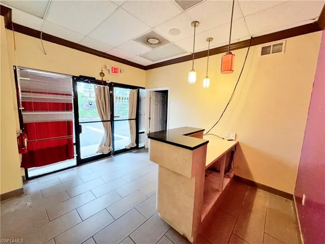 Kitchen with pendant lighting, a drop ceiling, dark tile patterned flooring, and kitchen peninsula