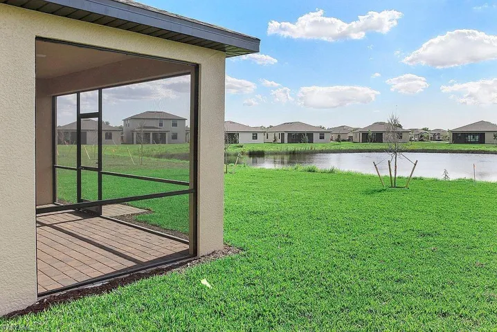 Screened patio with a paver floor and a stucco exterior, overlooking a body of water with a grassy bank