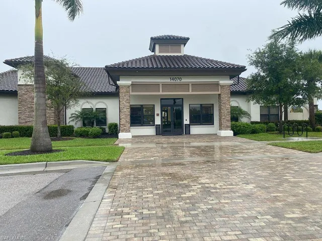 Tile roof, stone facade accents, arched window, paved brick driveway, and established landscaping