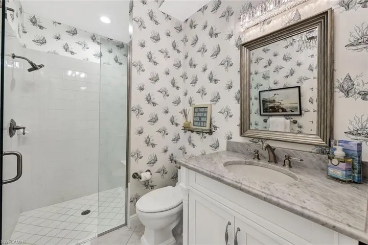 Bathroom featuring tile patterned flooring, toilet, vanity, and walk in shower