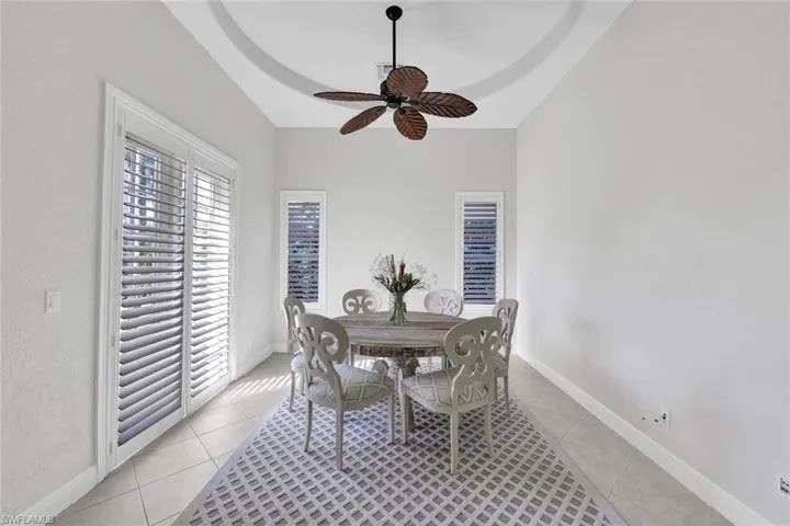 Dining space featuring ceiling fan, a wealth of natural light, light tile patterned floors, and a tray ceiling