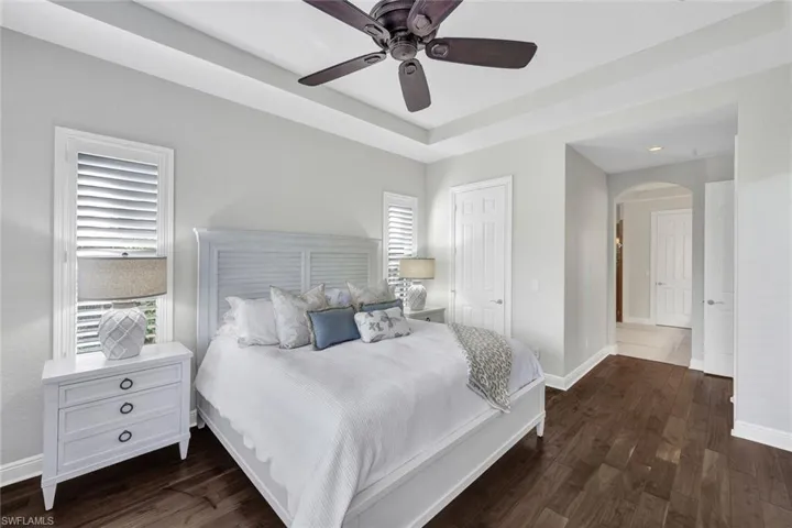 Bedroom with ceiling fan, dark hardwood / wood-style floors, and multiple windows