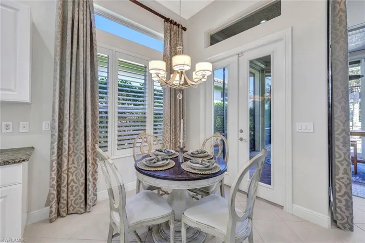 Tiled dining room with an inviting chandelier and french doors