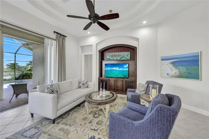 Tiled living room featuring ceiling fan and a tray ceiling