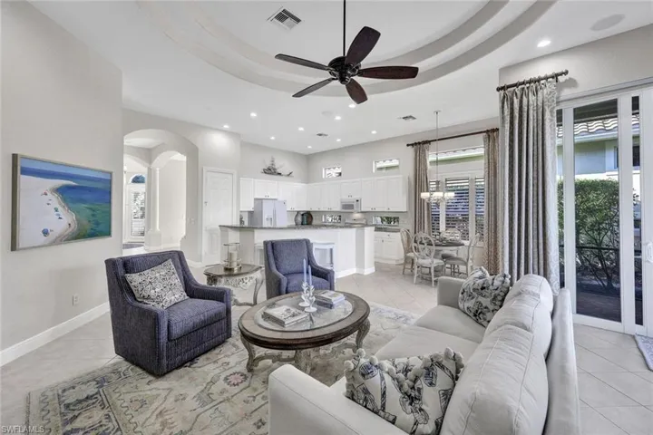 Tiled living room featuring ceiling fan and a raised ceiling