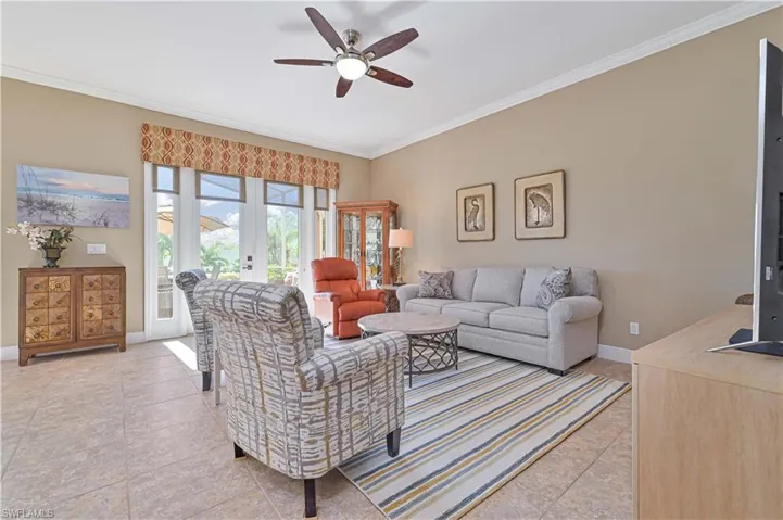 Tiled living room with ceiling fan, french doors, and crown molding