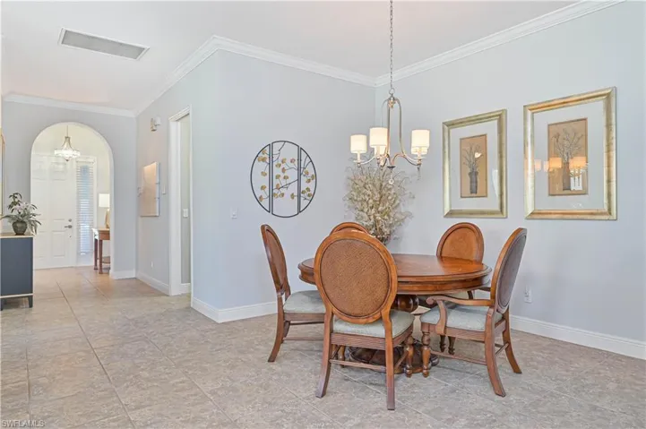 Dining room with ornamental molding and an inviting chandelier