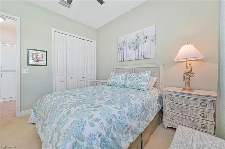 Carpeted bedroom with ceiling fan and a closet