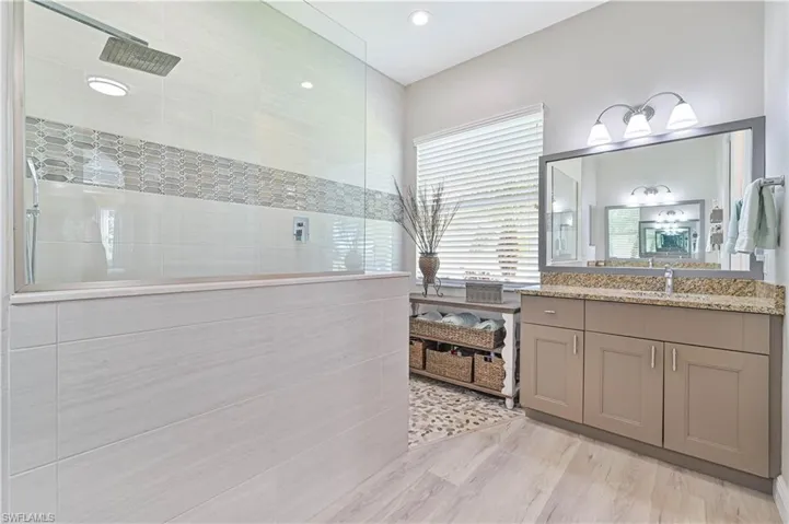 Bathroom featuring a tile shower, vanity, and hardwood / wood-style floors