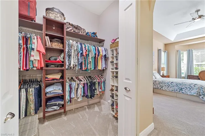 Walk in closet with ceiling fan and light colored carpet