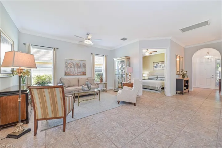 Tiled living room featuring ceiling fan, a healthy amount of sunlight, and ornamental molding