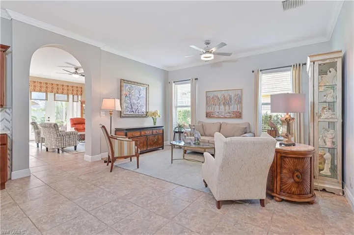 Living room featuring ceiling fan, light tile patterned floors, and ornamental molding