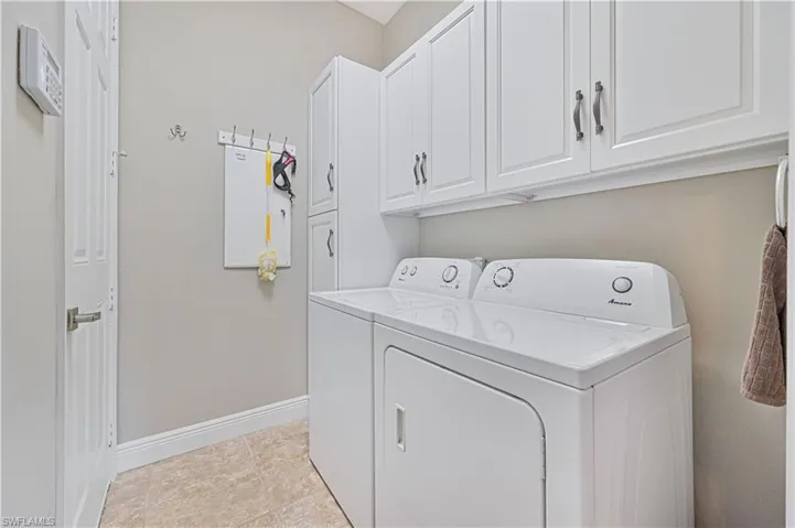 Washroom with washer and clothes dryer, cabinets, and light tile patterned floors