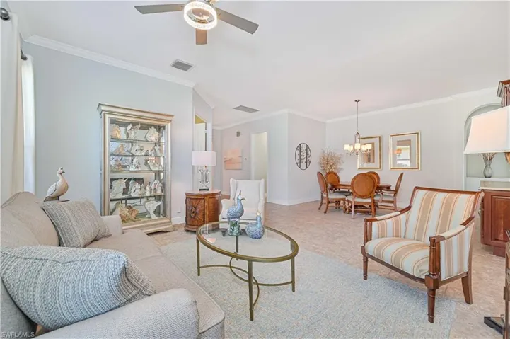 Living room with ceiling fan with notable chandelier and ornamental molding