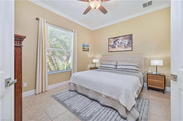 Tiled bedroom featuring ceiling fan and crown molding