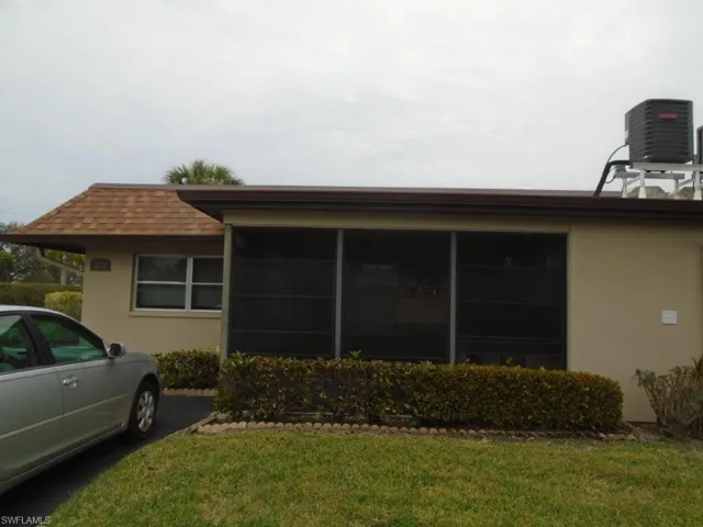 View of property exterior featuring stucco siding, a sunroom, central AC, and a yard
