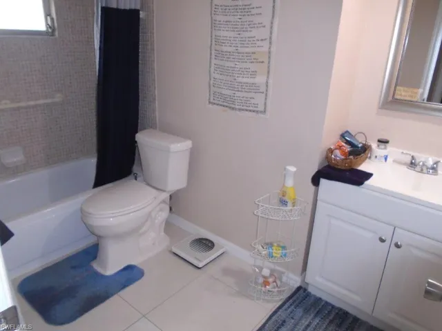 Full bathroom featuring baseboards, toilet, vanity, shower / bath combination with curtain, and tile patterned flooring