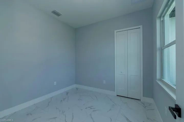 Unfurnished bedroom featuring baseboards, visible vents, and marble finish floor