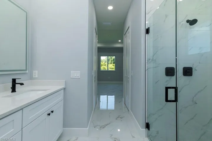 Full bathroom featuring baseboards, vanity, marble finish floor, a marble finish shower, and recessed lighting