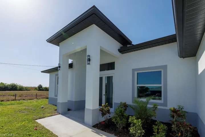 Entrance to property with a yard, stucco siding, and french doors
