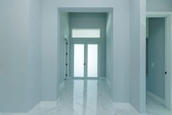 Corridor featuring baseboards and marble finish floor